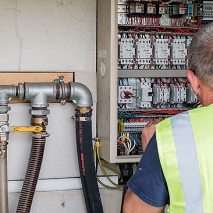 Engineer checking pipes at a control box