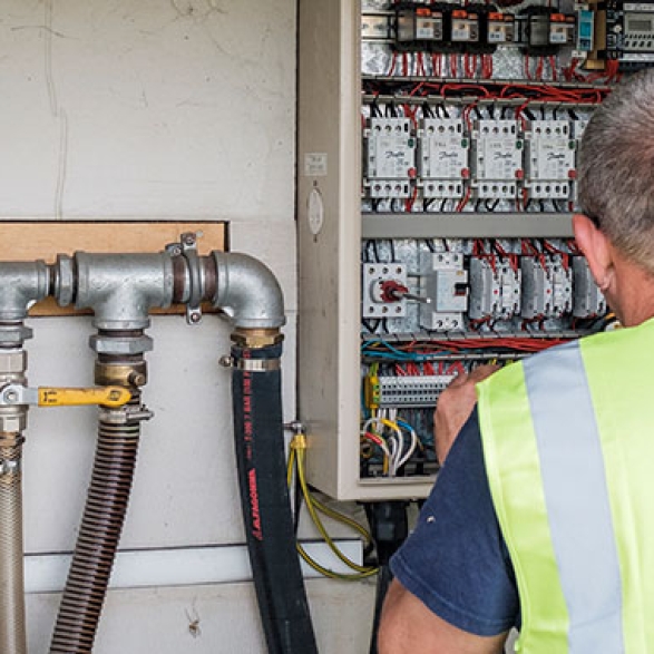 Engineer checking pipes at a control box