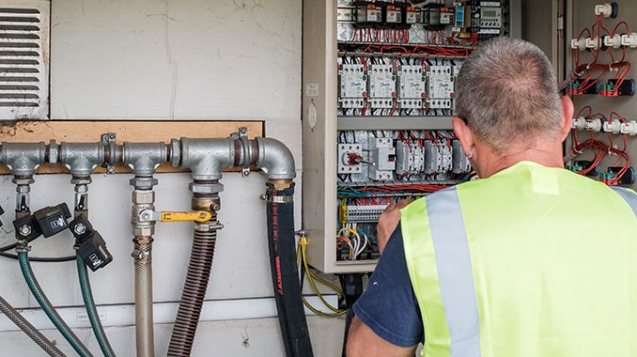 Engineer checking pipes at a control box