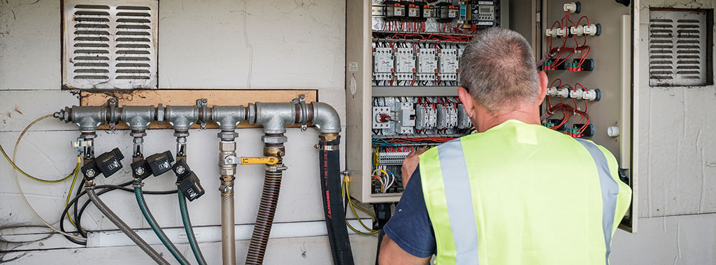 Engineer checking pipes at a control box