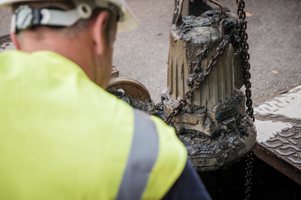 A sewage pump being taken out of a manhole