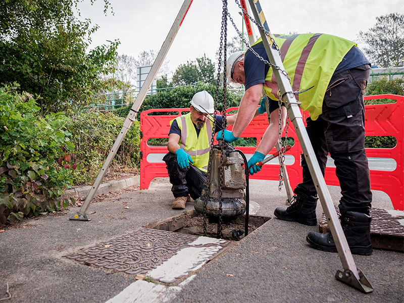 An image of two of our engineers lifting a sewage pump