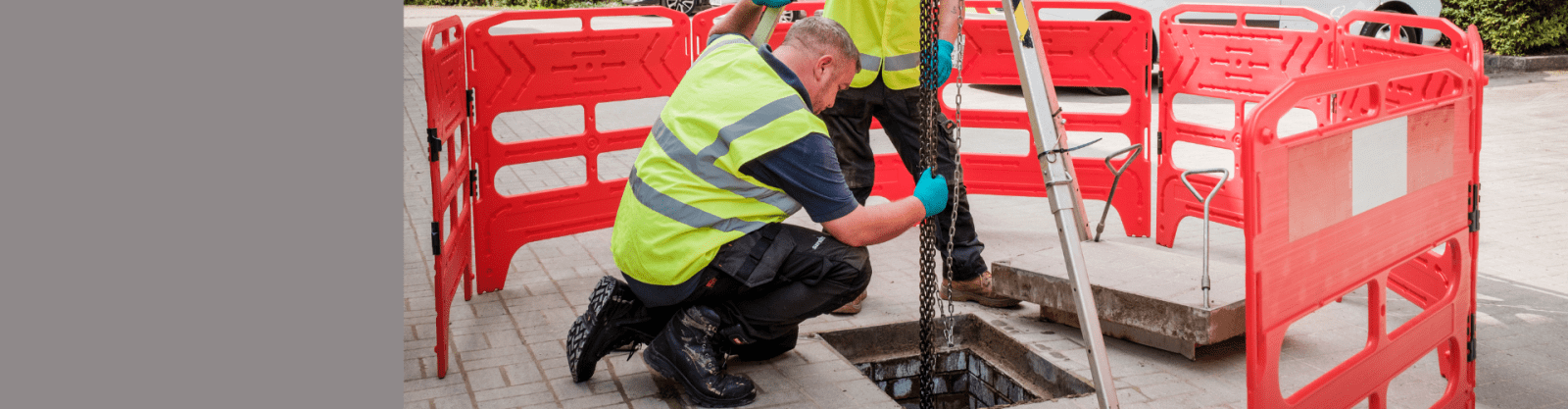 two engineers lowering a pump into a manhole