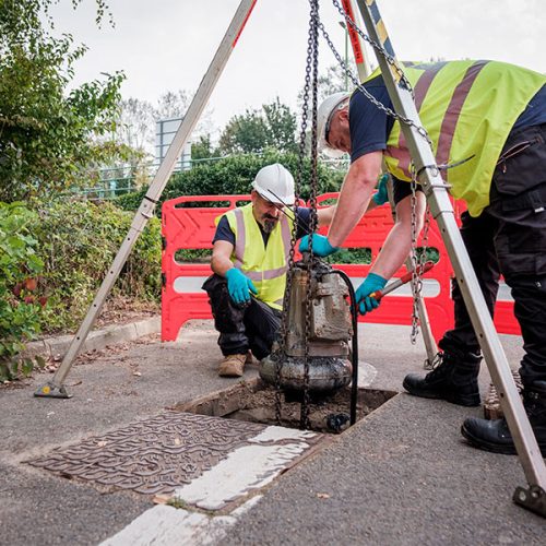 An image of two of our engineers lifting a sewage pump